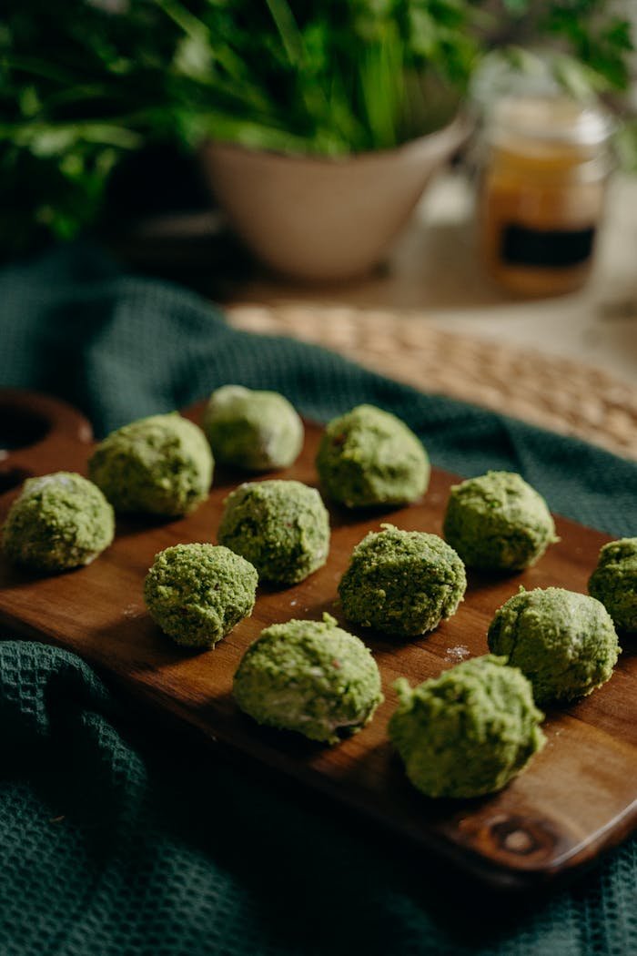 Services Freshly prepared green herb falafel on a wooden board, perfect for healthy vegan meals.